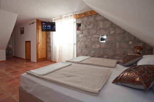 two beds in a room with a stone wall at Apartments Antica in Split