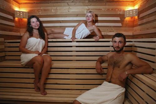 a man and two women sitting in a sauna at Le Vieux Logis in Yvoire