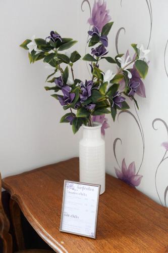 a vase filled with purple and white flowers on a table at Domaine des Lilas in Saint-Germain-Lembron
