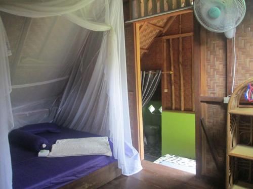 a small bed in a room with a curtain at On The Rocks Bungalows, Restaurant and Jungle Trekking Tours in Bukit Lawang