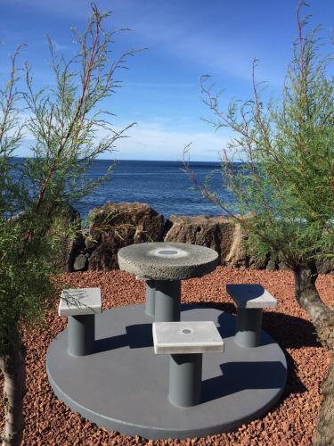 a table and benches in front of the ocean at Baia da Barca in Madalena
