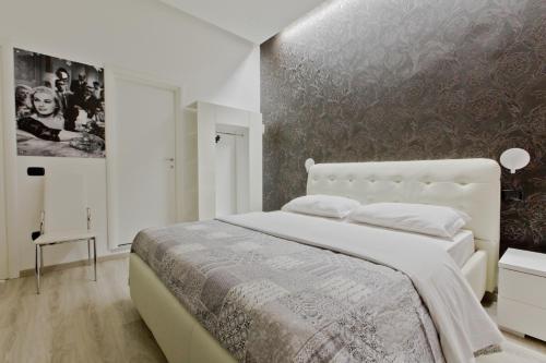 ローマにあるNew Rome house 2の白い大型ベッドと壁が備わるベッドルーム1室が備わります。