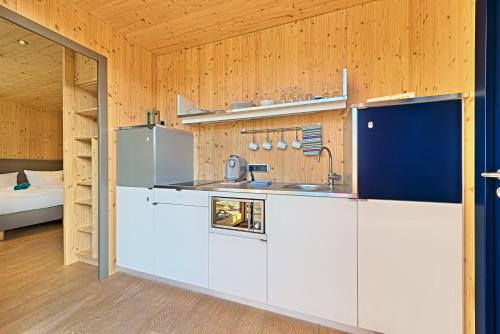 a kitchen with white cabinets in a room with a bed at mein kleinHOTEL in Herbstein