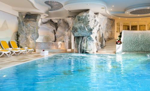 una piscina en un hotel con una cascada en Alpen Hotel Corona, en Vigo di Fassa