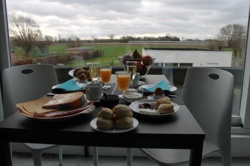 une table avec des assiettes de nourriture et des verres de jus d'orange dans l'établissement B&B Het Museum, à Berlaar