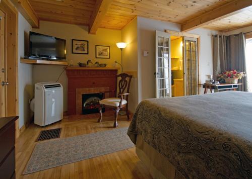 a bedroom with a bed and a fireplace and a television at Mackenzie Motel & Cottages in Shelburne