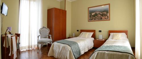 a bedroom with two beds and a chair and a painting at Hotel La Fenice in Chiari