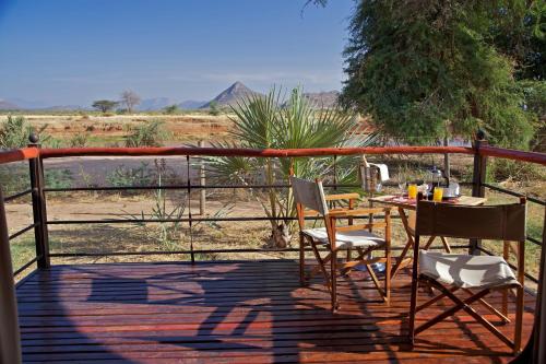 a patio with a table and chairs on a deck at Ashnil Samburu Camp in Archers Post