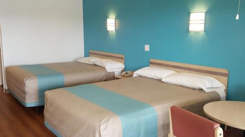 two beds in a hotel room with a table and a blue wall at Motel 6 Albany, OR in Albany
