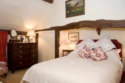 una camera da letto con un letto bianco con cuscini e un comò di The Old Manor House a Halford