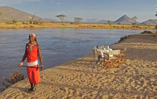 a woman standing on the bank of a river at Ashnil Samburu Camp in Archers Post