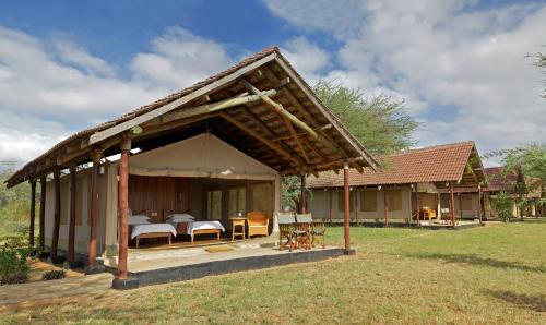 a guest house with a pavilion in a field at Ashnil Aruba Lodge in Tsavo