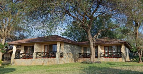 a house with a tree in front of it at Ashnil Aruba Lodge in Tsavo