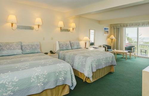 a hotel room with two beds and a balcony at Surfcomber On The Ocean in South Yarmouth
