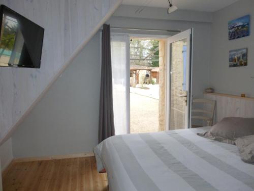 a bedroom with a bed and a sliding glass door at Aux Blanches Pierres in Fumel