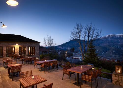 a patio with wooden tables and chairs and mountains at Aristi Mountain Resort in Aristi