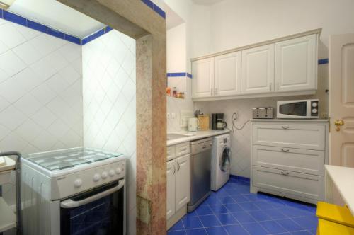 a kitchen with white cabinets and blue tile floors at Angola Apartment - 8Bedrooms in Lisbon