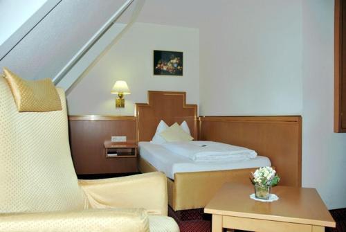 ein Hotelzimmer mit einem Bett und einem Stuhl in der Unterkunft Hotel-Gasthof Maisberger in Neufahrn bei Freising