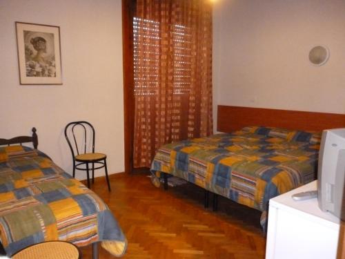 1 Schlafzimmer mit 2 Betten, einem Stuhl und einem Fenster in der Unterkunft Sansovino Bed and Car in Florenz