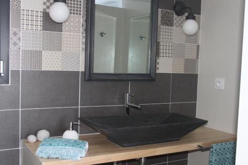uma casa de banho com um lavatório preto e um espelho em Au Fil des Cévennes em Saint-Jean-de-Maruéjols-et-Avéjan