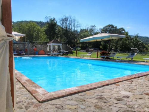 ein großer blauer Pool mit Stühlen und einem Sonnenschirm in der Unterkunft Belvilla by OYO Casa Rovello in Todi
