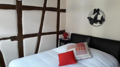 Schlafzimmer mit einem weißen Bett und einem roten Kissen in der Unterkunft Appartement avec terrasse "BARTHOLDI" in Colmar
