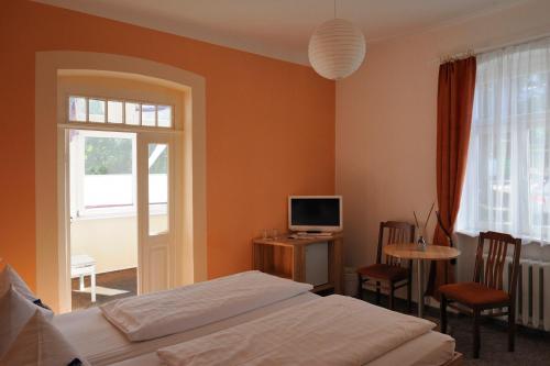 a bedroom with a bed and a table and a television at Pension Am Klünderberg in Binz