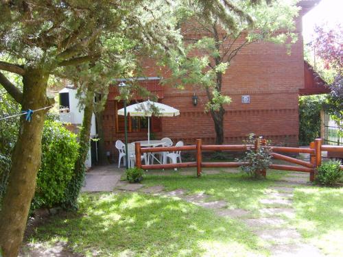 a wooden fence with a table and an umbrella in a yard at Cabañas El Maiten in San Clemente del Tuyú