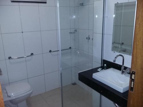 a bathroom with a shower and a toilet and a sink at Alfon Hotel in Itabira