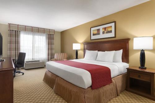 a hotel room with a large bed and a desk at Country Inn & Suites by Radisson, St Peters, MO in Saint Peters