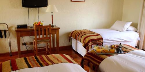 a hotel room with two beds and a desk with a tray of fruit at Hotel Terraviña in Santa Cruz