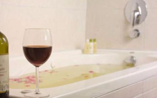 a glass of wine sitting next to a bath tub at Le Vele Resort in Grace Bay