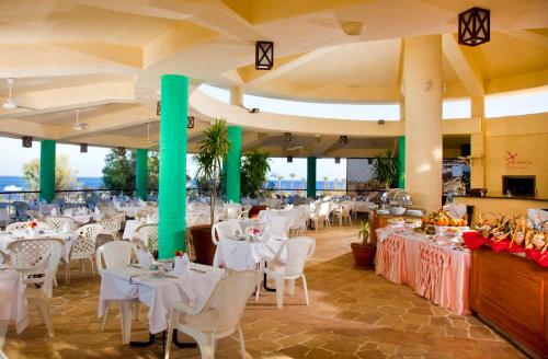 Xperience Hill-Top Beach Resort في شرم الشيخ: مطعم بطاولات بيضاء وكراسي بيضاء