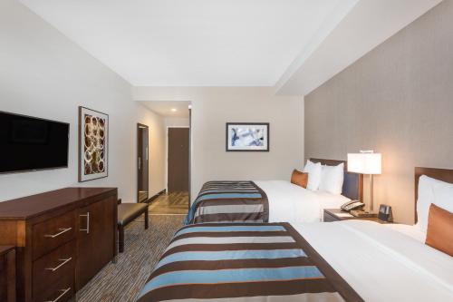a hotel room with two beds and a flat screen tv at Wingate by Wyndham Miami Airport in Miami
