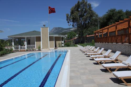 a swimming pool with lounge chairs and a flag at Padok Premium Hotel & Stables in Gökova