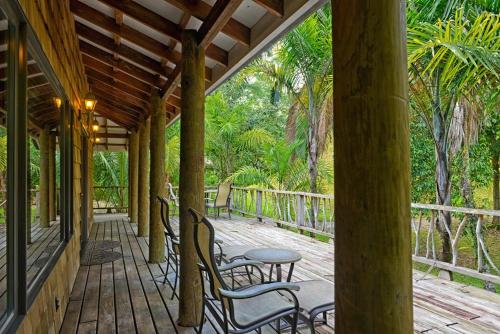 a wooden porch with chairs and a table on it at Chan Chich Lodge in Gallon Jug