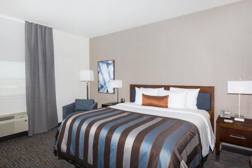 a hotel room with a large bed and a chair at Wingate by Wyndham Miami Airport in Miami