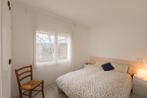 a bedroom with a bed and a chair and a window at Acogedor apartamento en el centro de Llançà in Llança