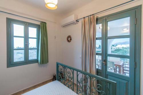 a bedroom with a green door and windows at Alma Libre Villas in Kastraki Naxou