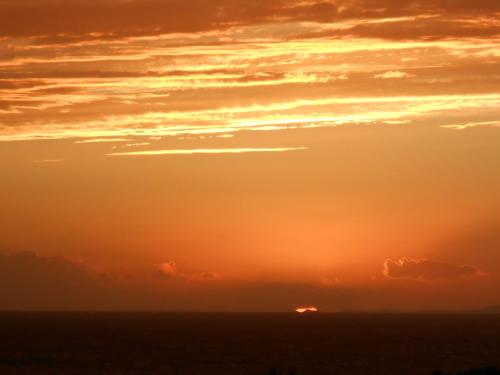 a sunset over the ocean with a ship in the distance at Alma Libre Villas in Kastraki Naxou