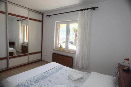 a bedroom with a bed and a large window at Cres Sučić Apartments in Cres