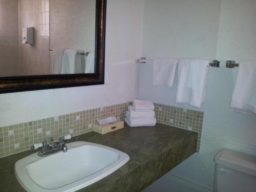 y baño con lavabo, espejo y toallas. en Carravalla Inn, en Melfort