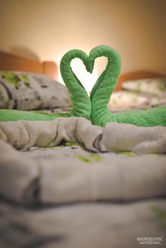 two green towels with hearts on a bed at Guest House Vila Banjica in Pirot