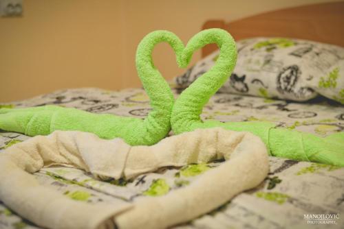 two green towel swans on top of a bed at Guest House Vila Banjica in Pirot