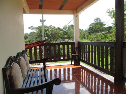 a porch with a bench and a hammock on it at Hospedaje y Camping Buena Vista in San Agustín