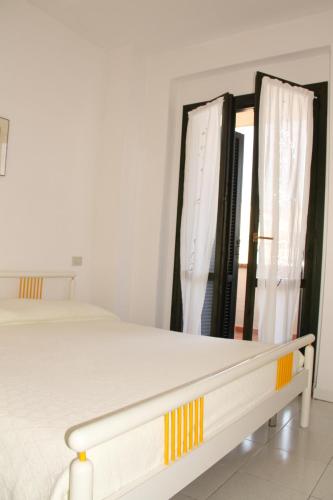 a white bedroom with a bed and a window at Roberta Apartment in Marcelli