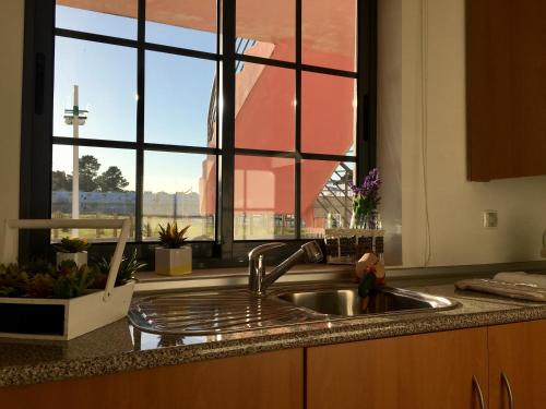 a kitchen with a sink and a large window at SR Palmela Village Studios II in Quinta do Anjo
