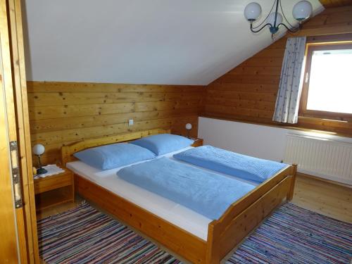 Schlafzimmer mit einem Bett mit blauer Bettwäsche und einem Fenster in der Unterkunft Baby- und Kinderhof Aicherbauer in Seeham