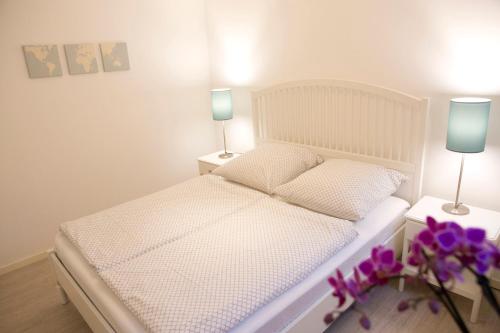 フレンスブルクにあるAltstadtquartierのベッドルーム1室(ランプ2つ、紫の花付)