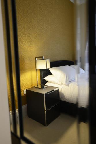 a bedroom with a bed and a lamp on a night stand at The Devon Court in Torquay